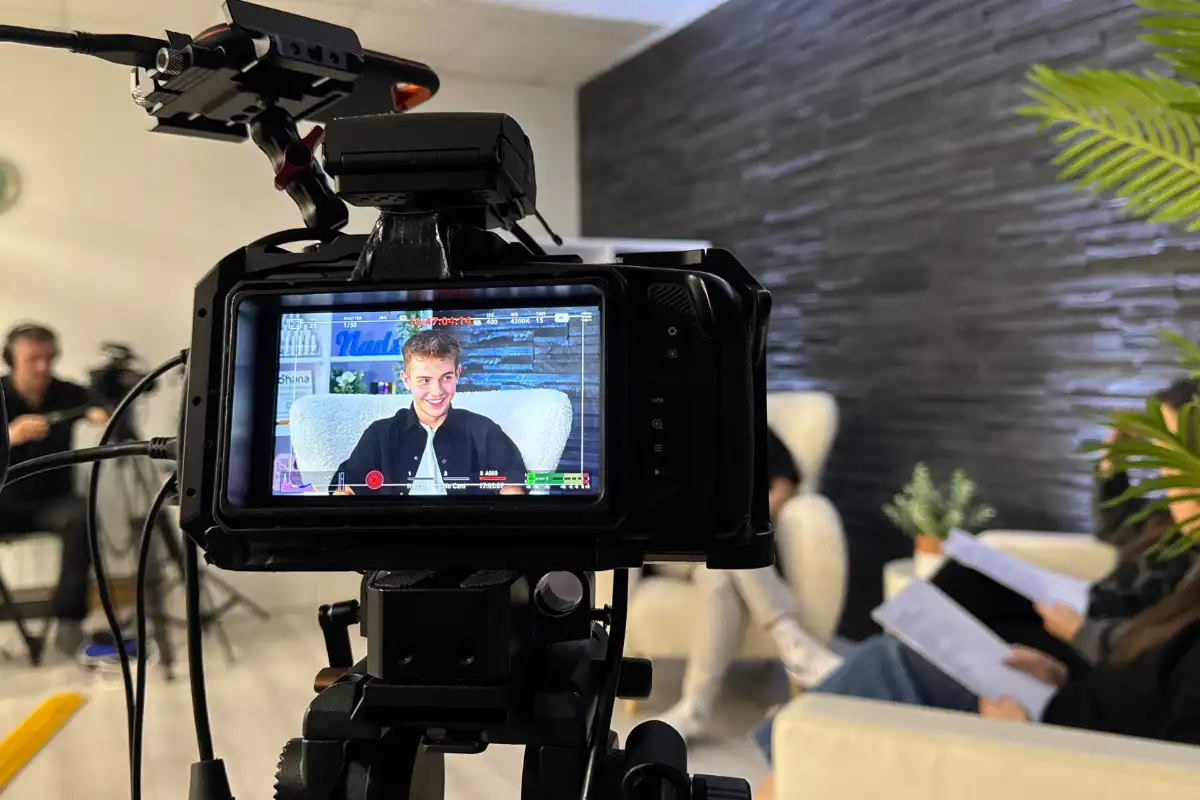 Professional video camera recording a video podcast interview, with the guest visible on the camera monitor