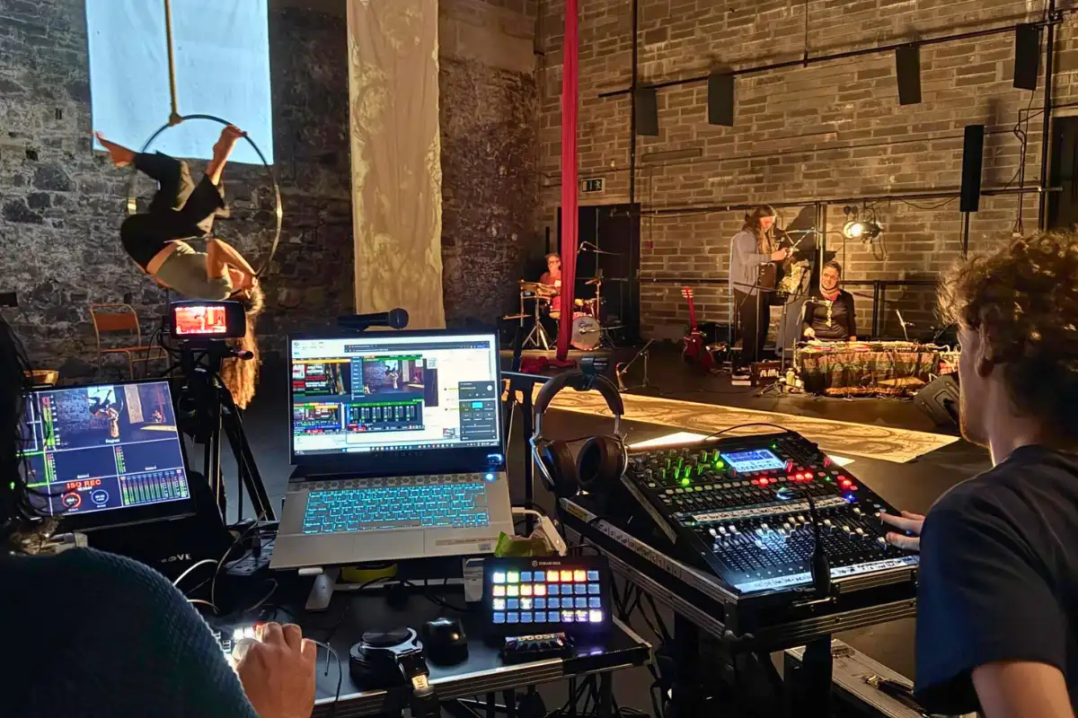 An audio mixer and streaming console being operated by a crew member to manage a live event broadcasting for a stage performance