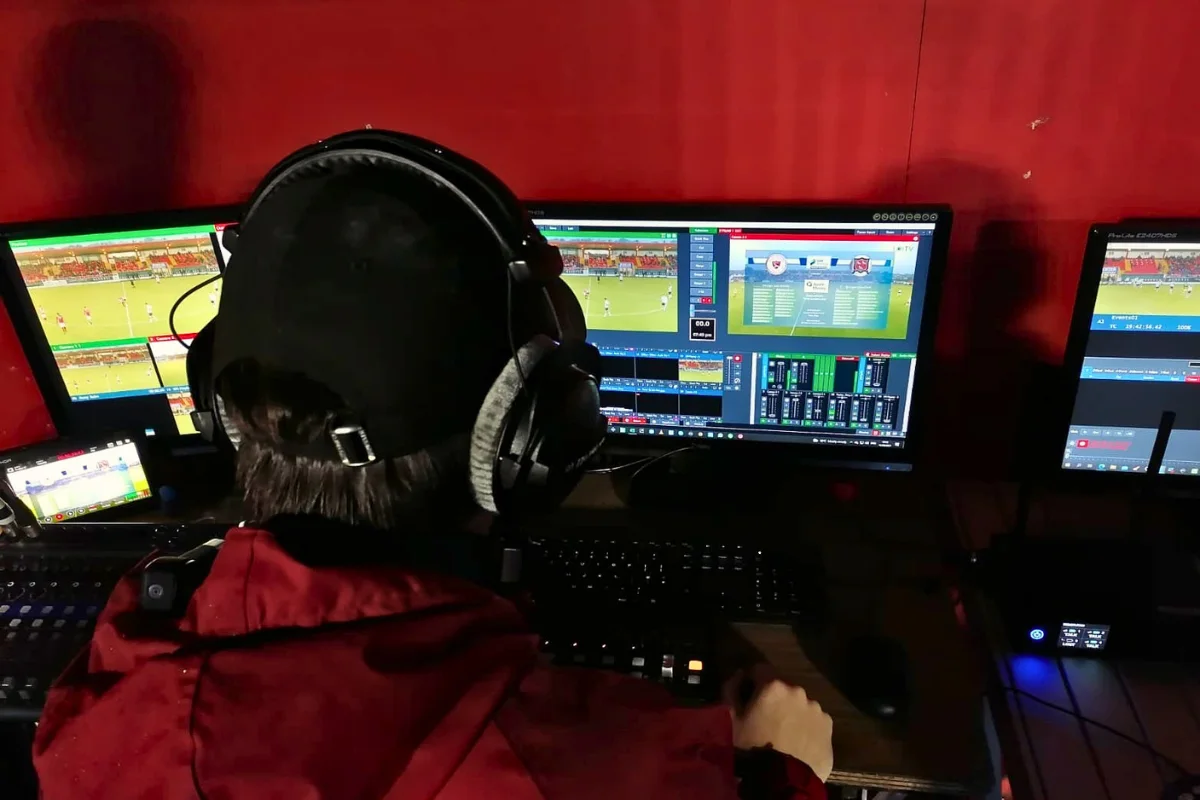 An AV technician wearing headphones monitoring a sports match broadcast, highlighting technical setups for professional live stream events