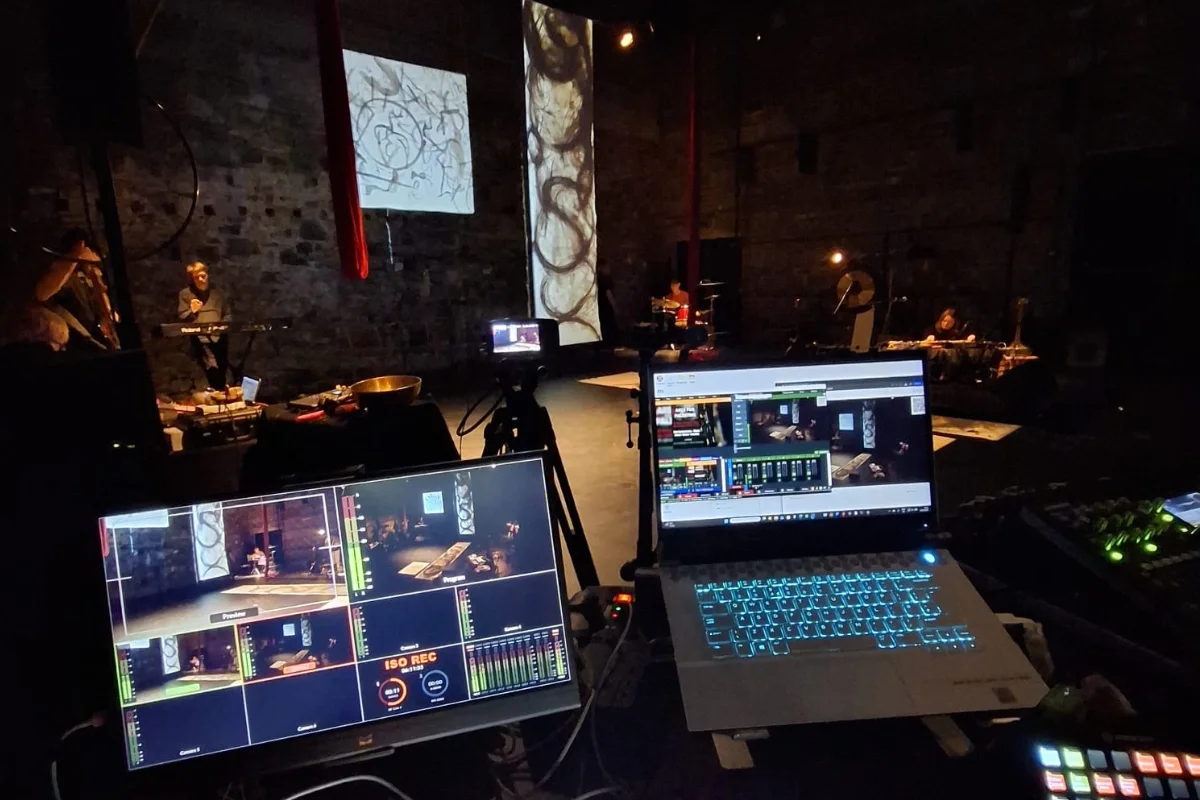 A technical production desk featuring switcher software and laptops for high-end live event broadcasting inside a theater venue