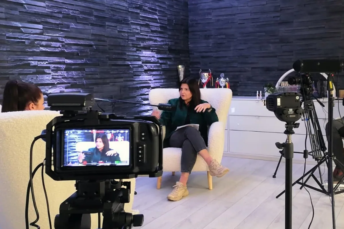 Two people recording a video podcast in a studio, with professional cameras and microphones set up around them.